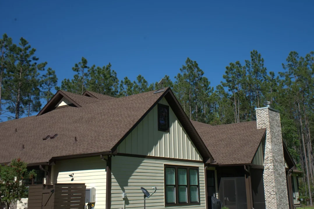 New architectural shingle roof on residential home with brown shingles and stone chimney