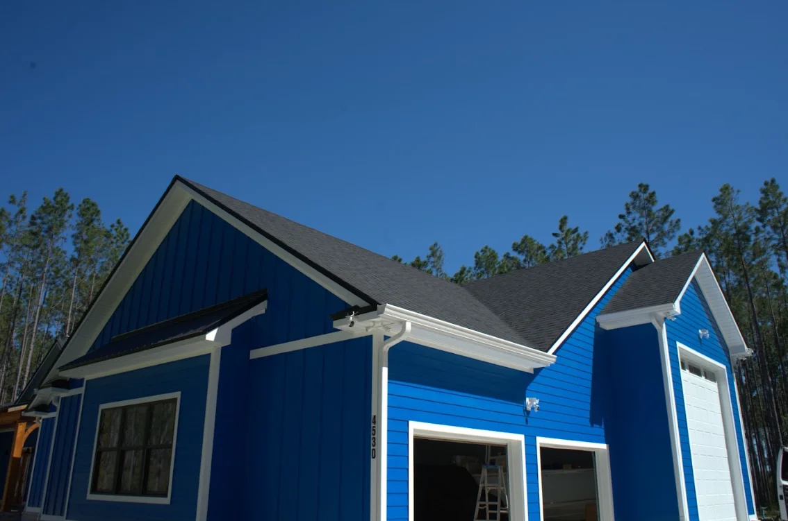 New gray asphalt shingle roof on blue residential home with white trim and gable details
