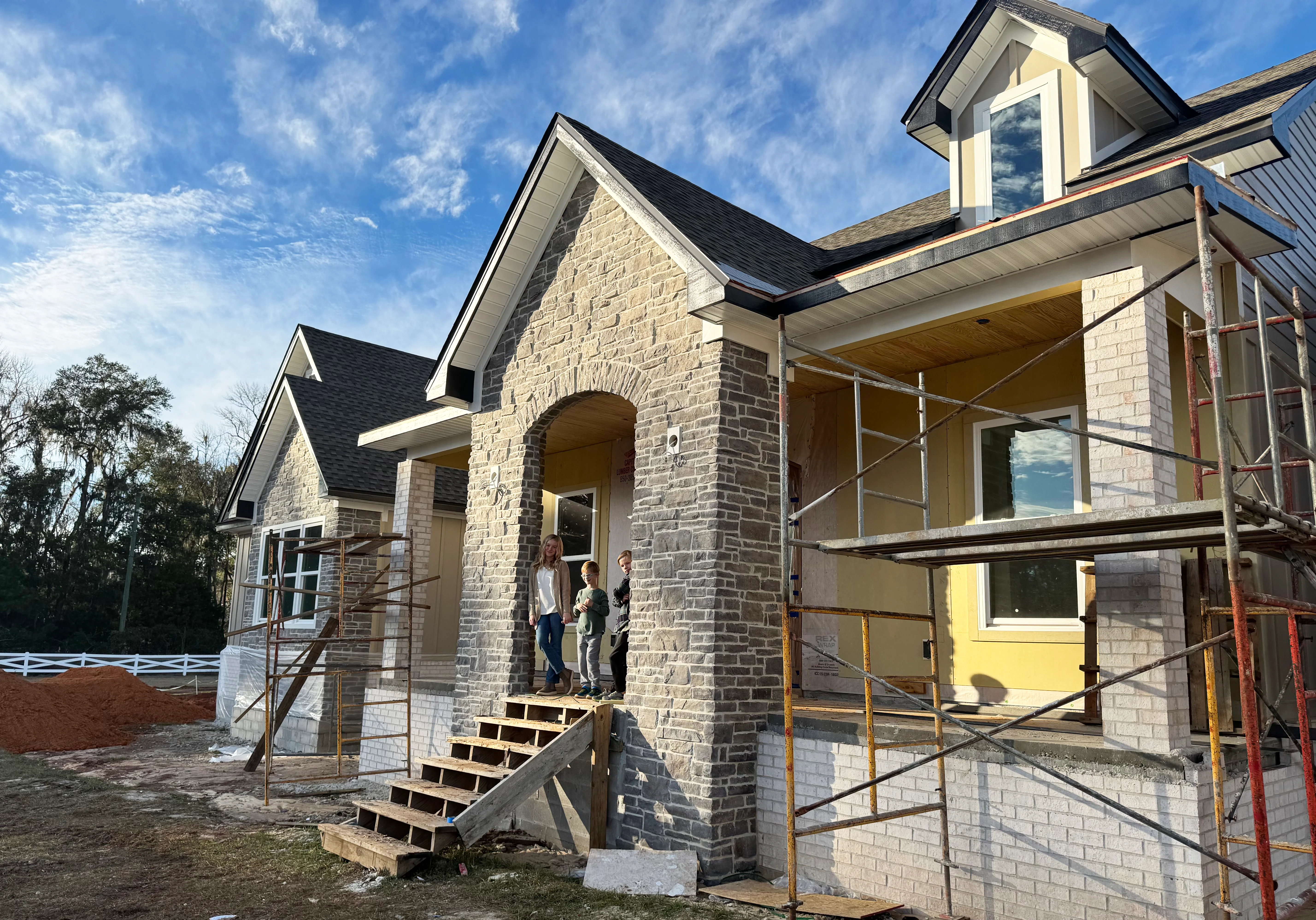 New home construction with freshly installed dark gray asphalt shingle roof and stone brick exterior in Tallahassee