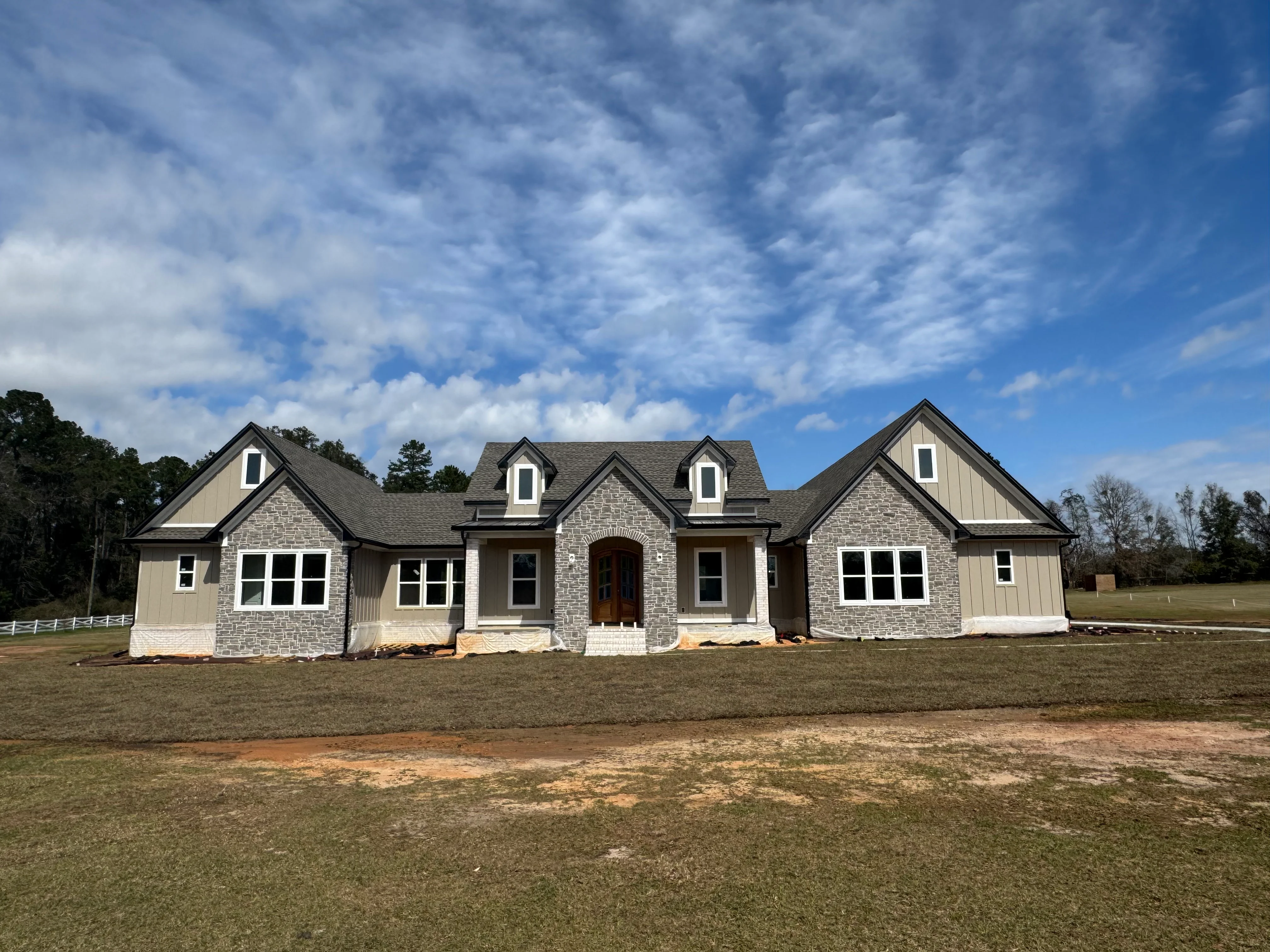 New residential home with multi-gable charcoal gray roof and stone exterior in Tallahassee
