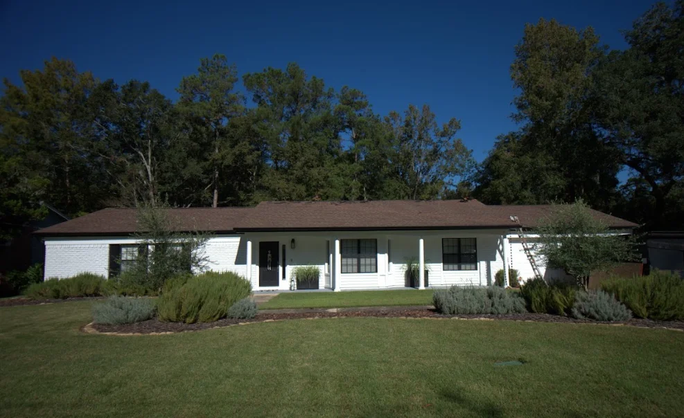 White ranch home with new brown asphalt shingle roof and manicured landscaping