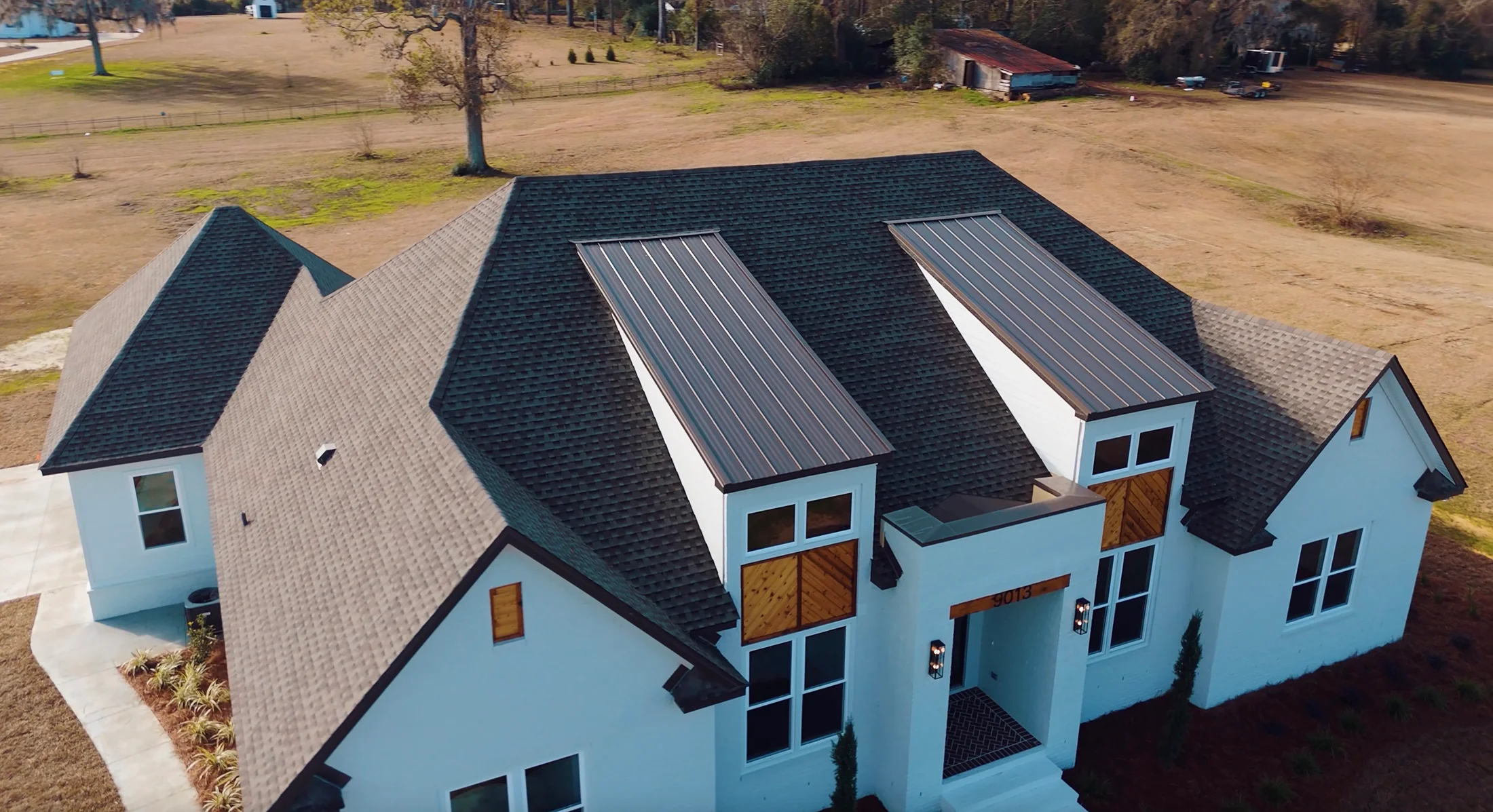 Aerial view of residential home with new dark shingle roof and metal roof accents in Tallahassee