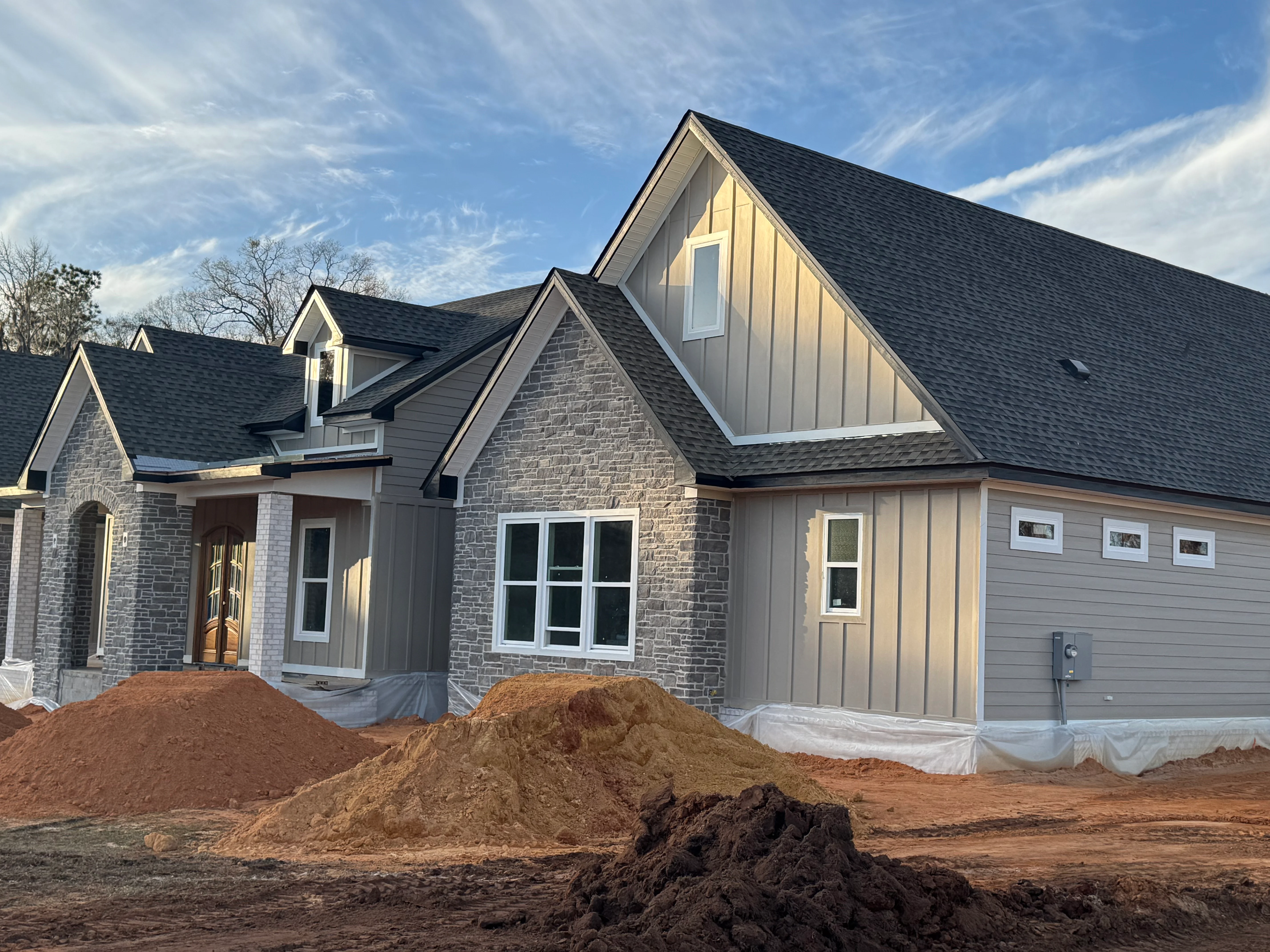 New residential home with dark gray architectural shingle roof installation and stone veneer facade