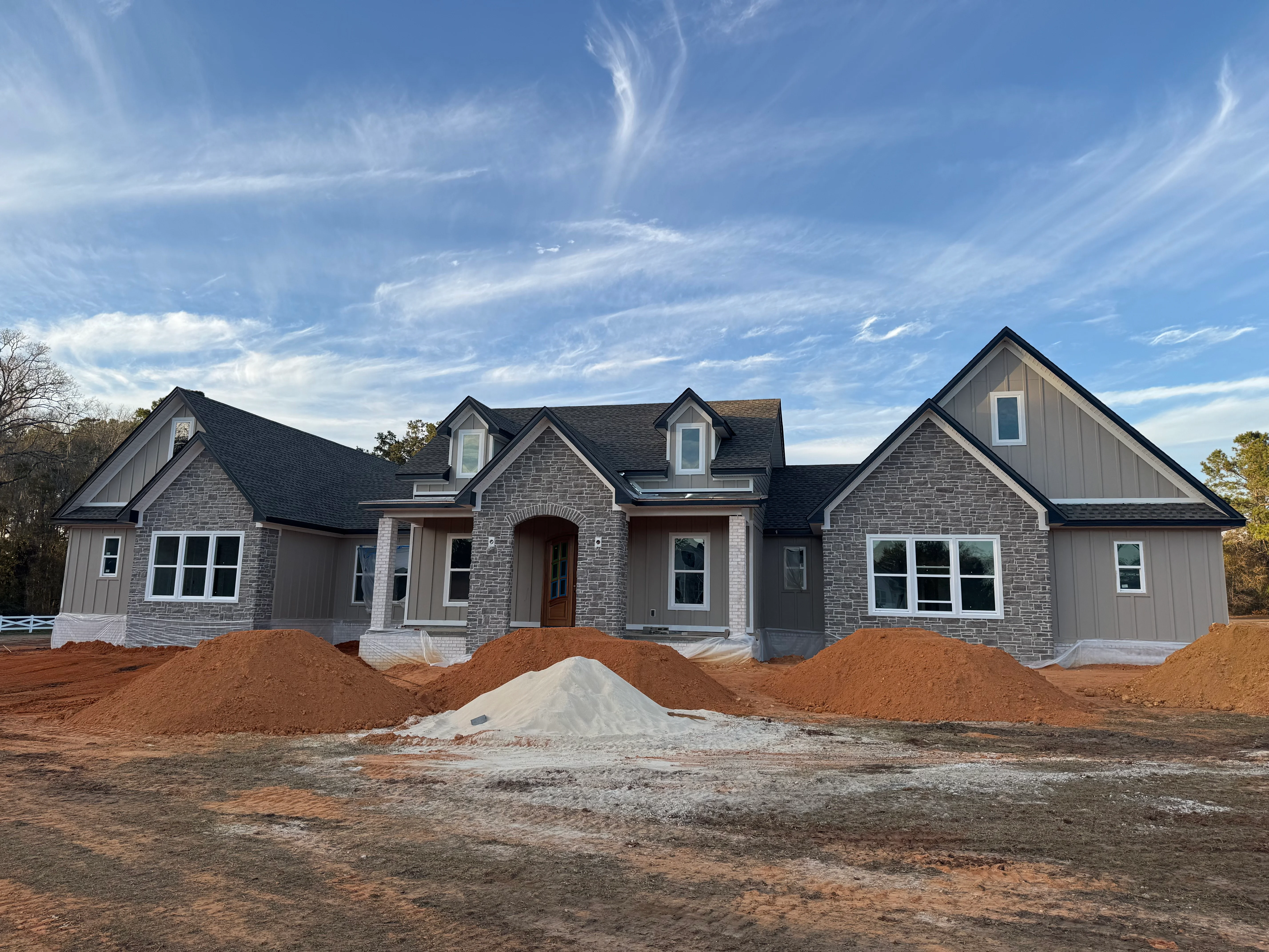 New home with dark asphalt shingle roof installation, stone exterior, multiple dormers