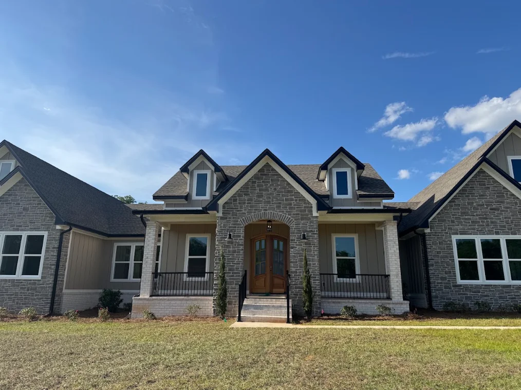New asphalt shingle roof on modern stone home with dormers and metal railings