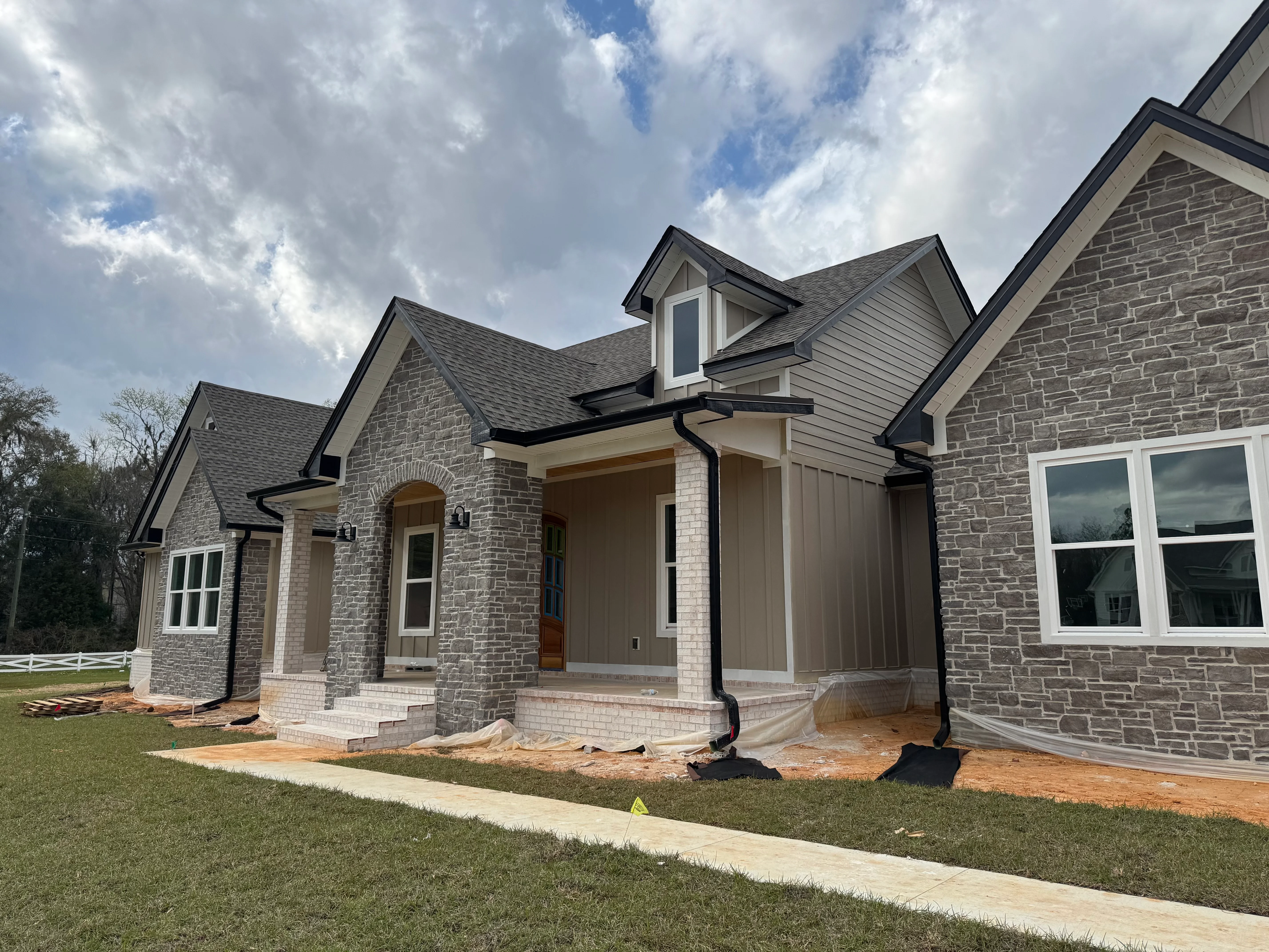 New residential home with charcoal gray architectural shingle roof and stone exterior in Tallahassee