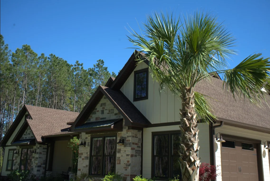 Two-story home with new gray architectural shingle roof, stone facade, and palm tree landscaping