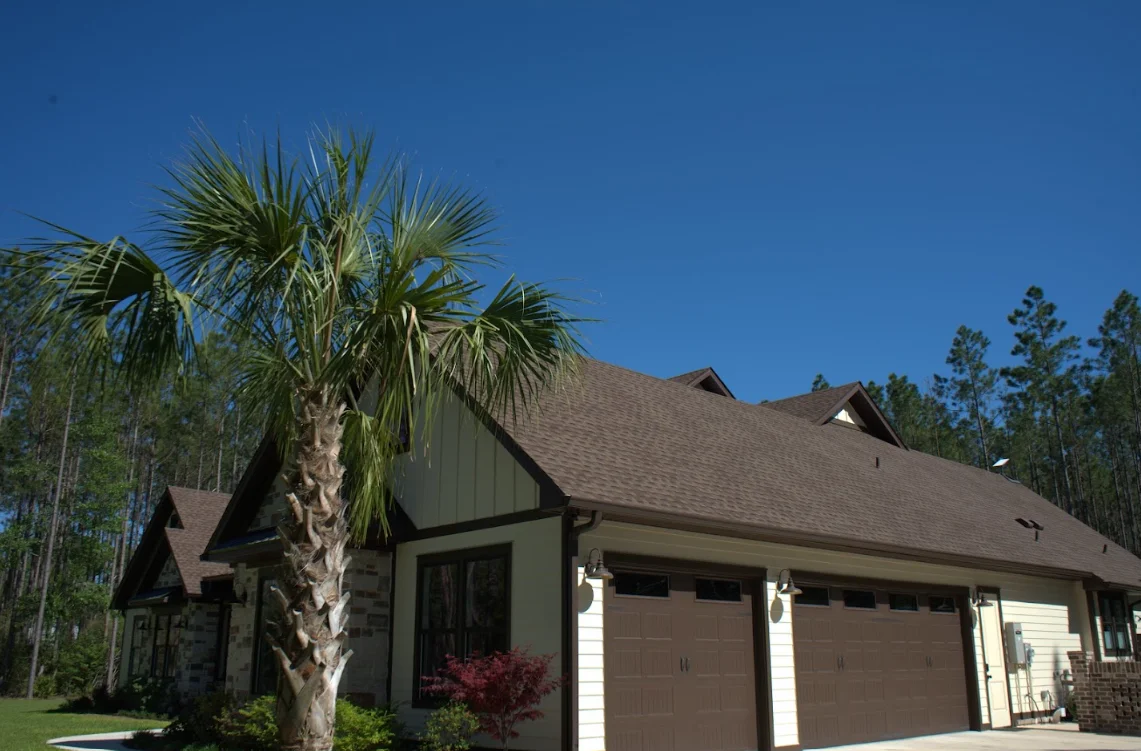 Two-story home with new charcoal gray asphalt shingle roof and palm tree landscaping