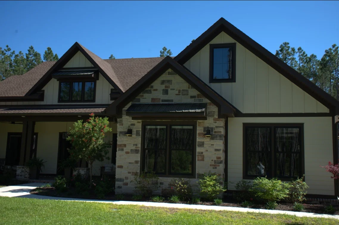 Modern home with dark peaked roofs, stone accents, and multiple gables against clear blue sky