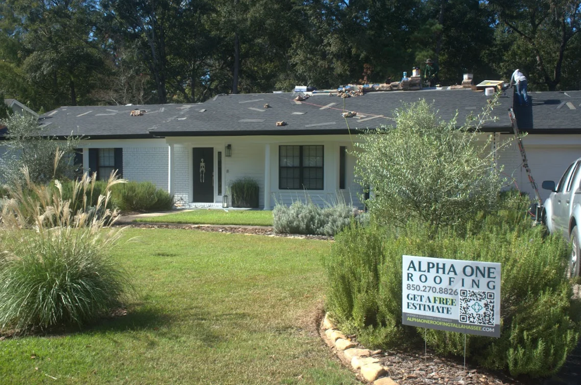 White brick home with new gray asphalt shingle roof during installation in Tallahassee