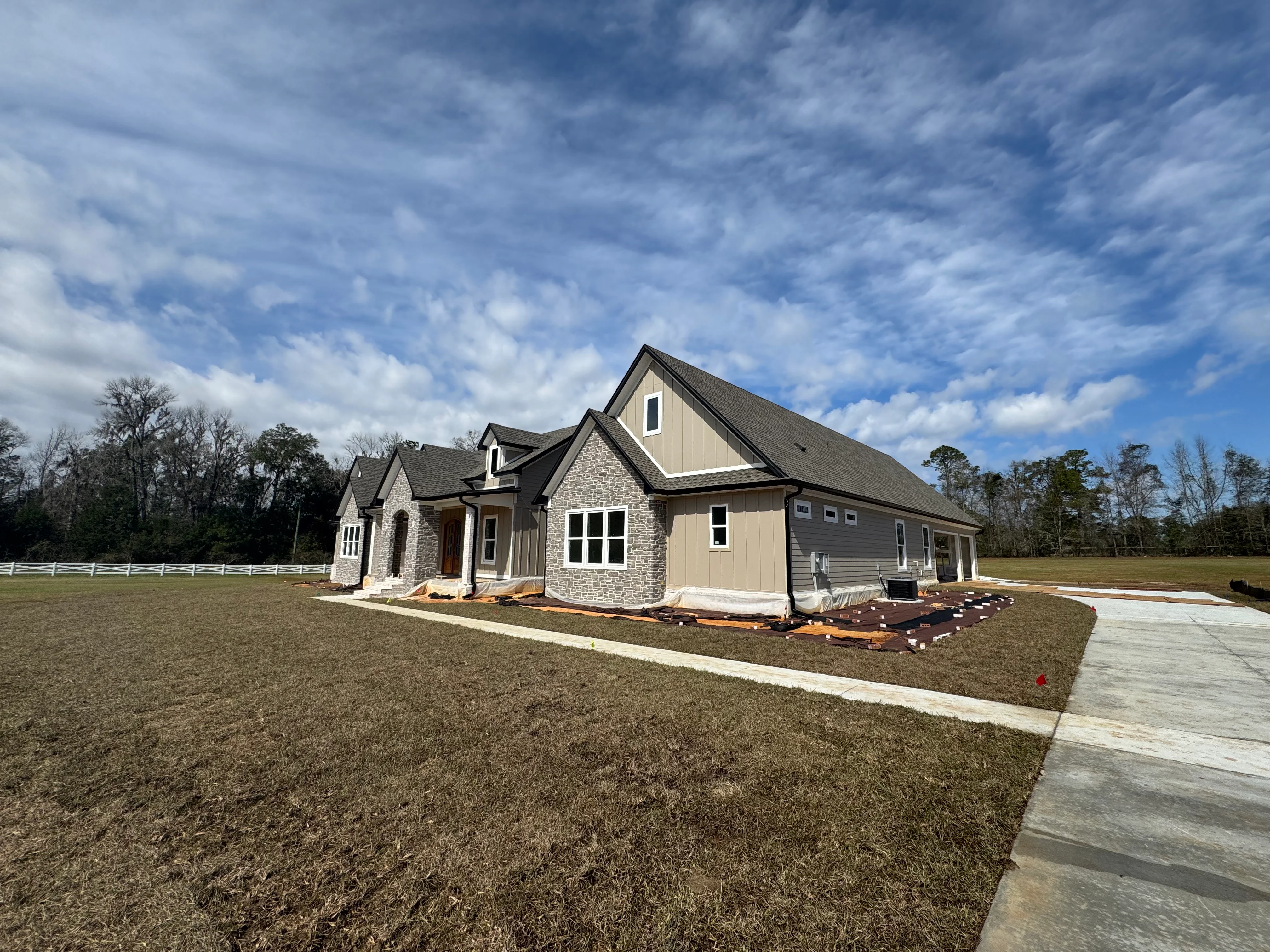 New custom home with multi-gable roof installation featuring stone and siding exterior